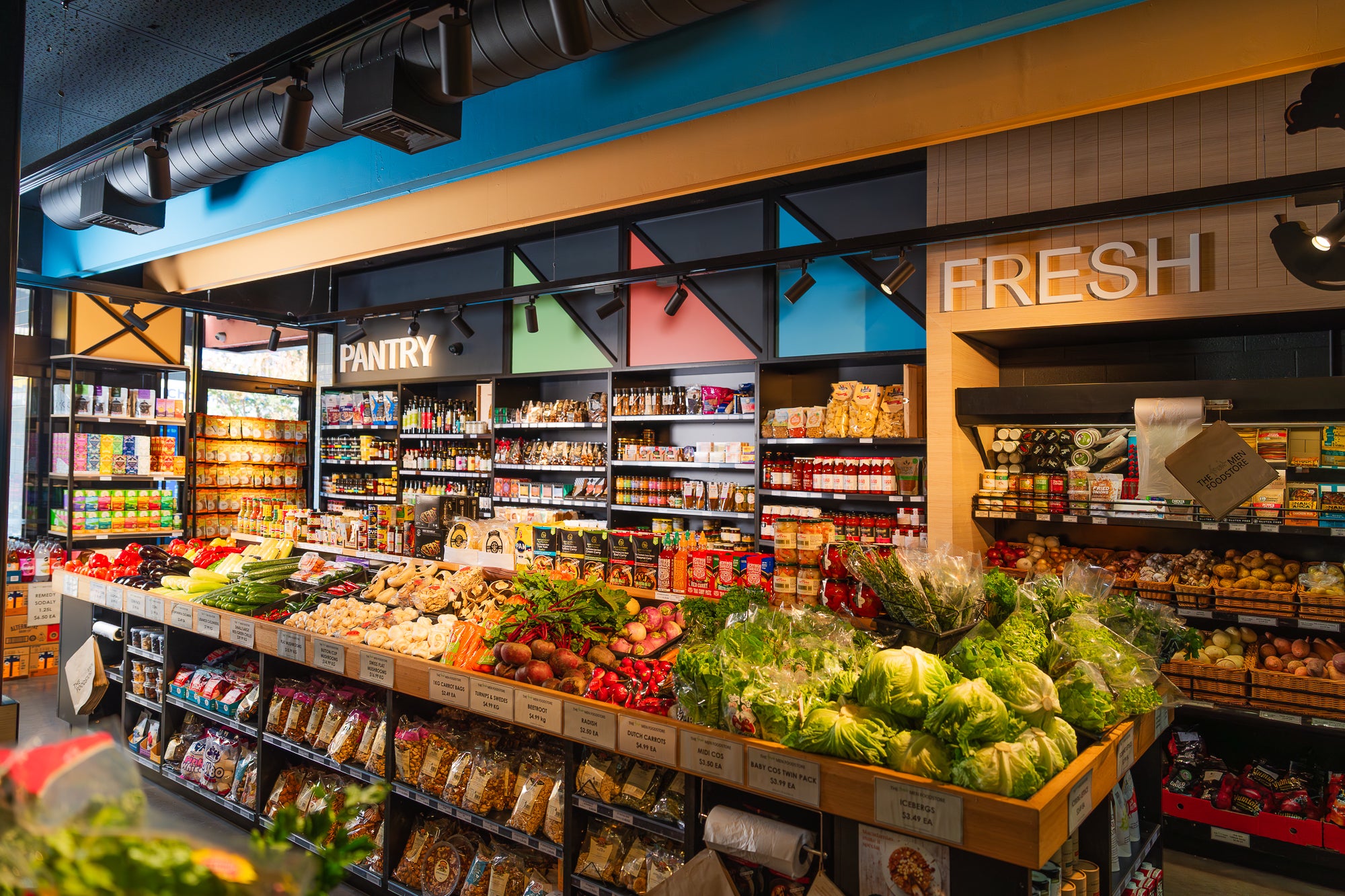 Supermarket interior with fresh produce and shelves stocked with products.